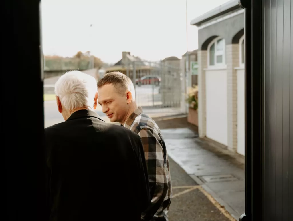 Church planter in a chequered shirt talking to an older man dressed in a suit jacket