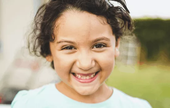 A closeup of the face of a young girl smiling full of joy straight into the camera.